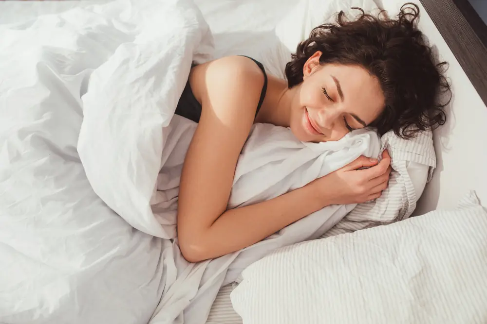 Woman sleeping. High angle view of beautiful young woman lying in bed and keeping eyes closed while covered with blanket. Stock photo