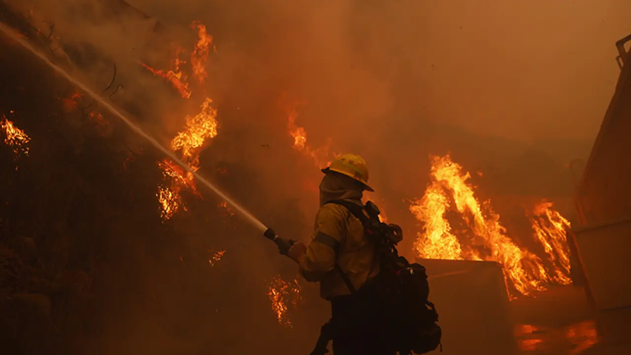 A firefighter battles the advancing Palisades Fire around a structure in the Pacific Palisades neighborhood of Los Angeles Tuesday, Jan. 7, 2025. (AP Photo/Etienne Laurent)