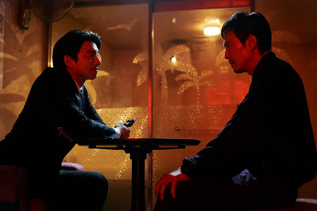 Lee Jung-jae as Seong Gi-hun sits at a table with a man wearing a black suit in Season 2 of ‘Squid Game’