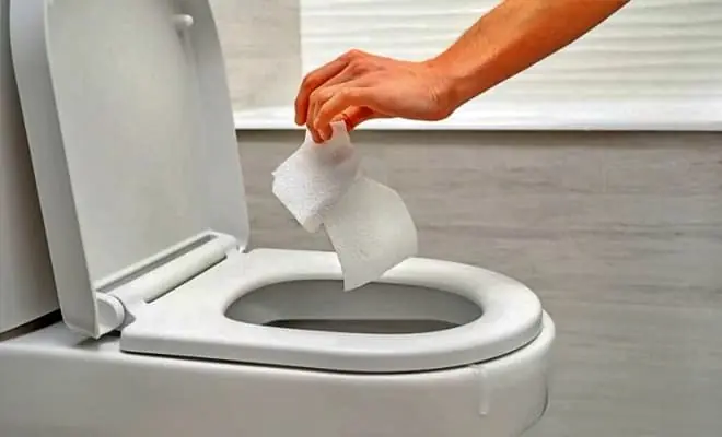 Why should you put a piece of paper in the toilet before using it?