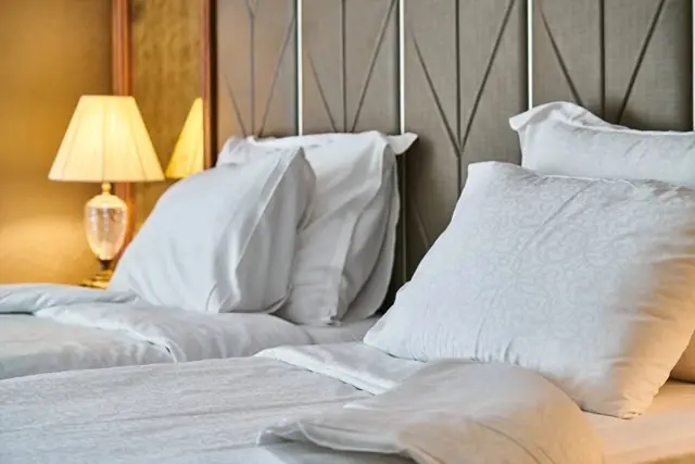Why do most hotel beds have four pillows instead of two, and how are the extra pillows used?